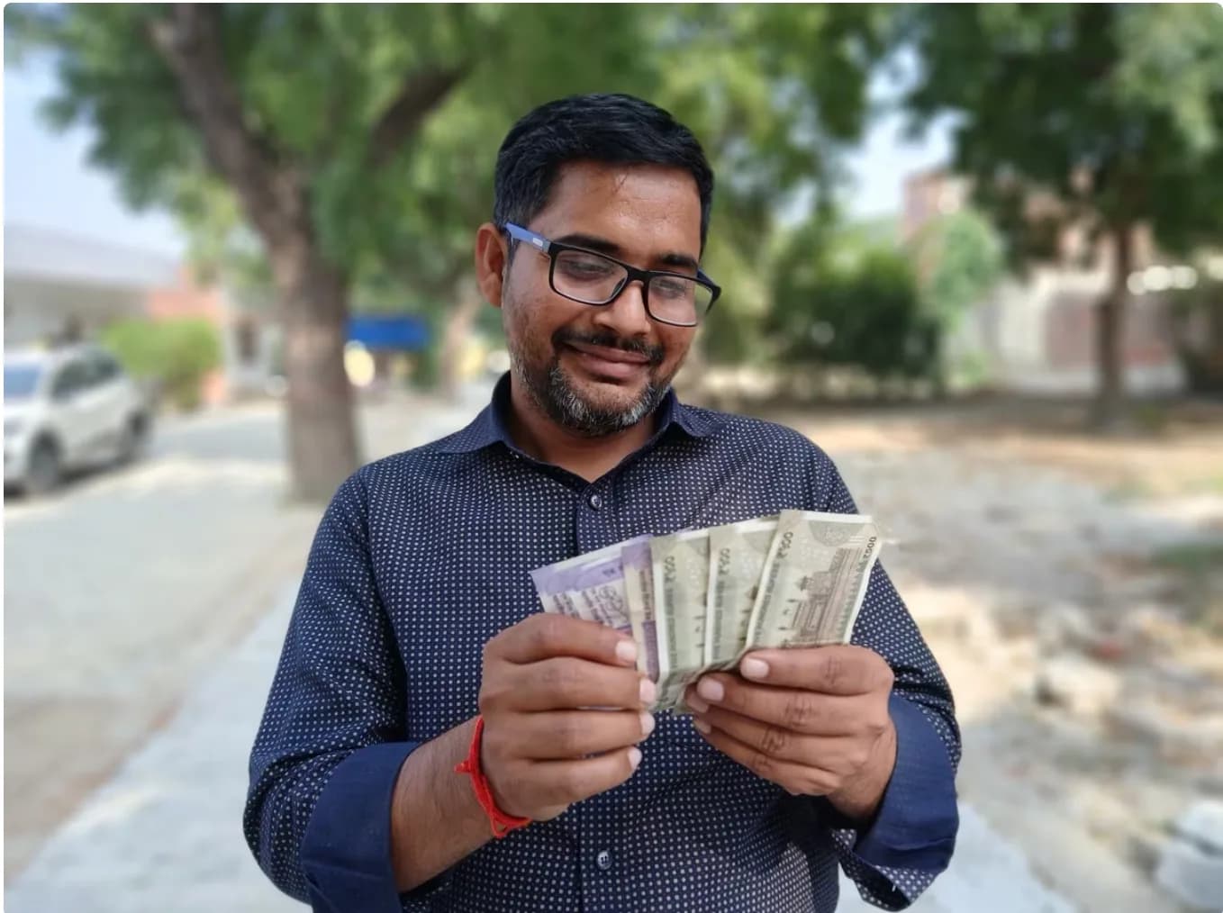 एक आदमी भारतीय रुपये के नोट पकड़े हुए है।