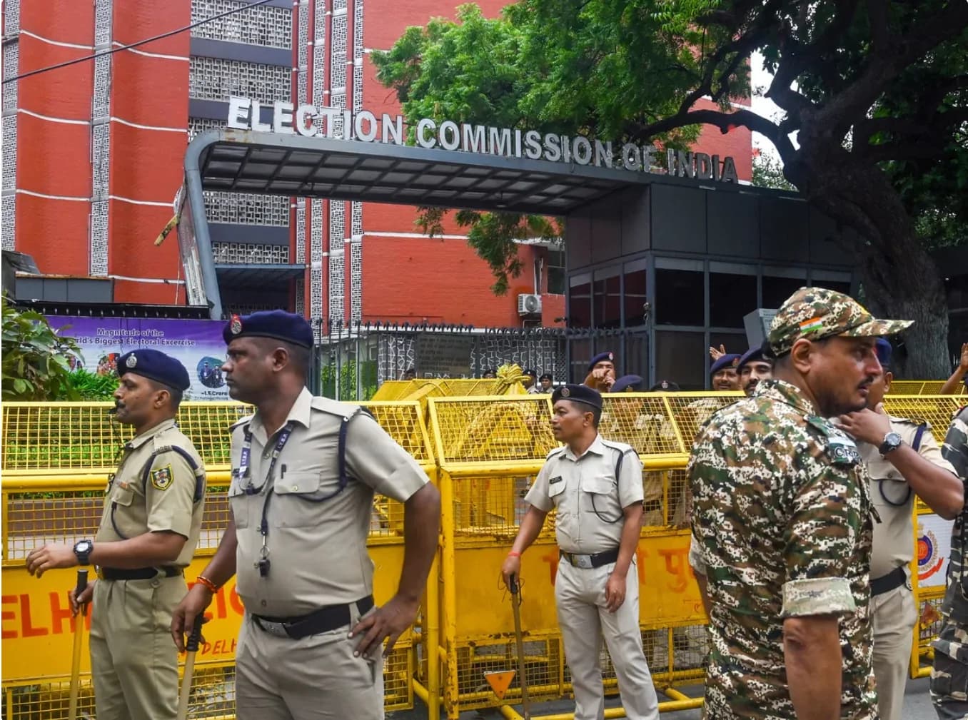 भारत निर्वाचन आयोग के बाहर पुलिसकर्मी और सुरक्षाकर्मी पीले बैरिकेड के पास खड़े हैं।