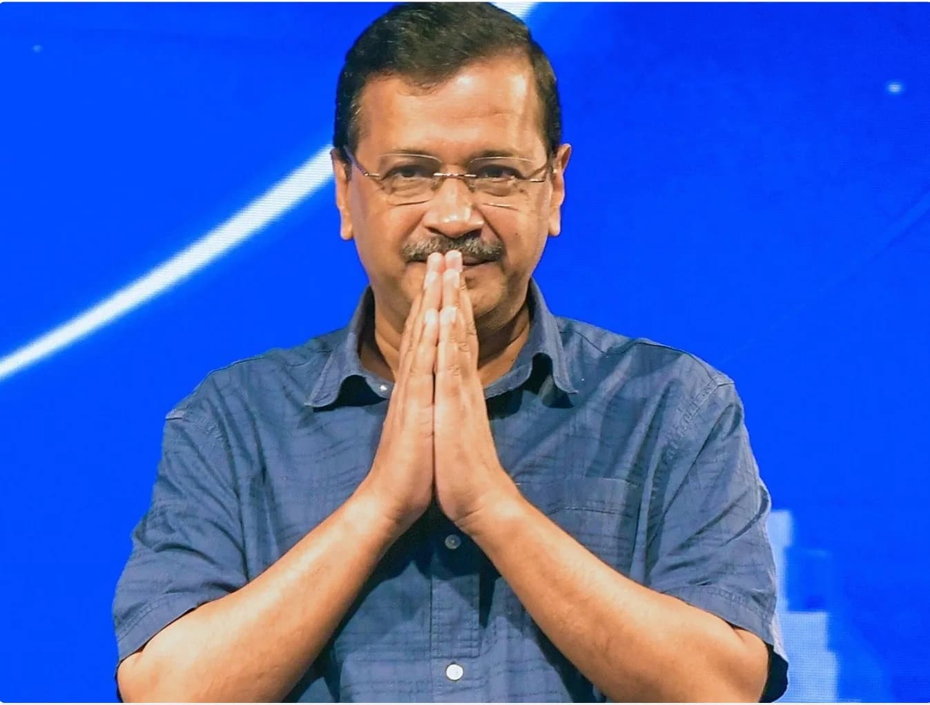 एक व्यक्ति नमस्ते की मुद्रा में हाथ जोड़कर कैमरे की ओर देख रहा है।