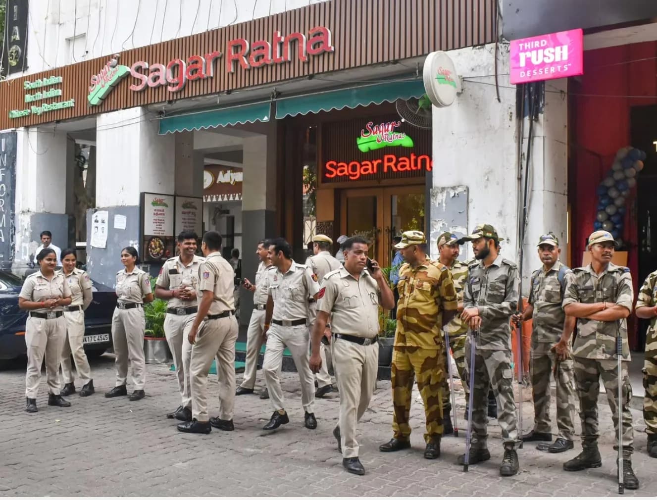 सड़क पर पुलिस अधिकारी और सैनिक खड़े हैं, उनके पीछे सागर रत्ना रेस्तरां है।