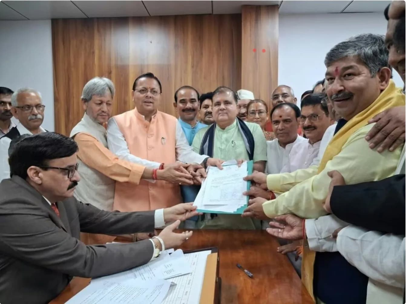 एक समूह के लोग एक मेज पर कागजात पकड़े हुए हैं।