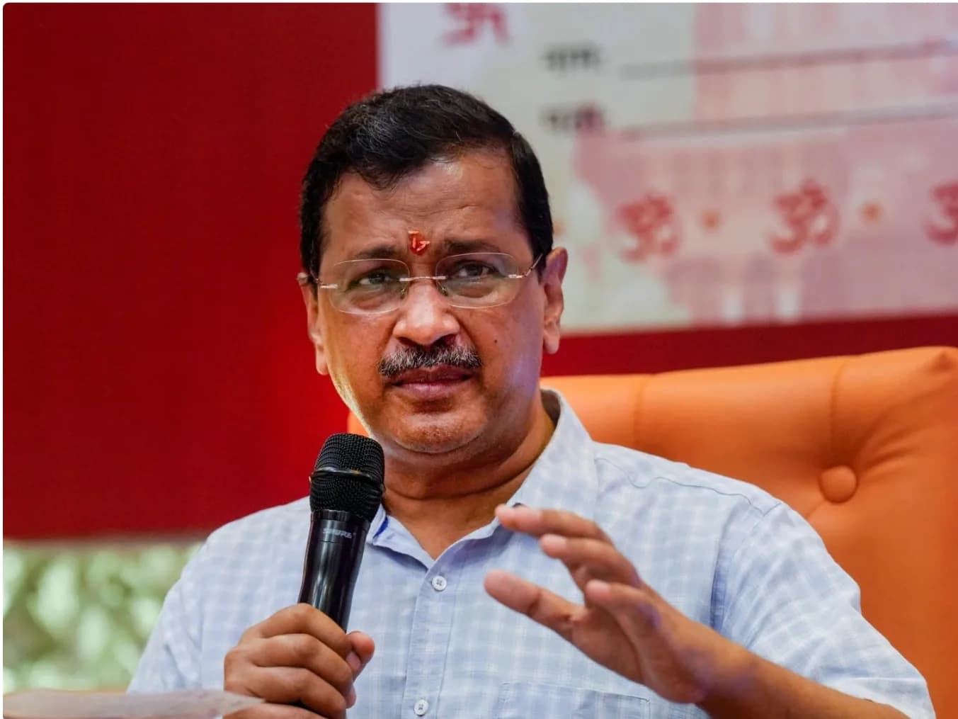एक व्यक्ति माइक्रोफ़ोन पकड़े हुए बोल रहा है।
