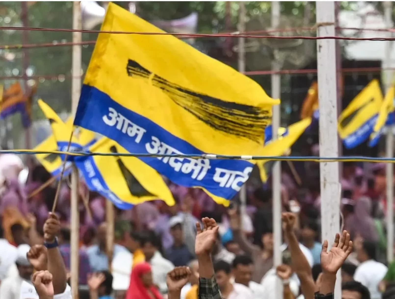 आम आदमी पार्टी के झंडे लहराते हुए और लोग प्रदर्शन कर रहे हैं।
