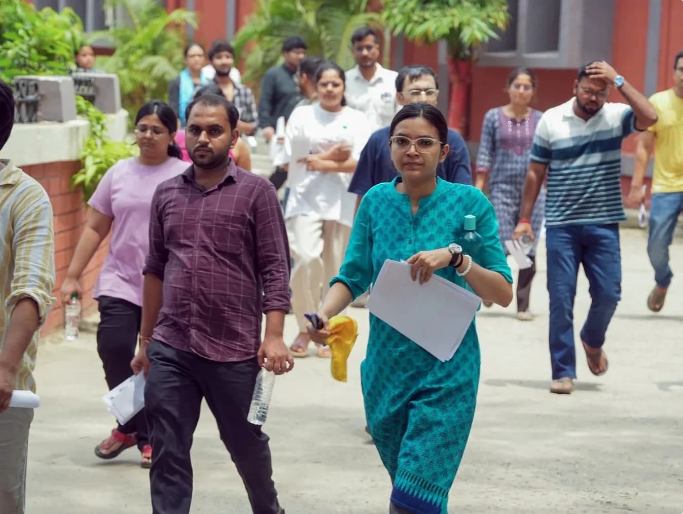 कई लोग एक सड़क पर चल रहे हैं, जिसमें एक महिला सामने की ओर देख रही है।