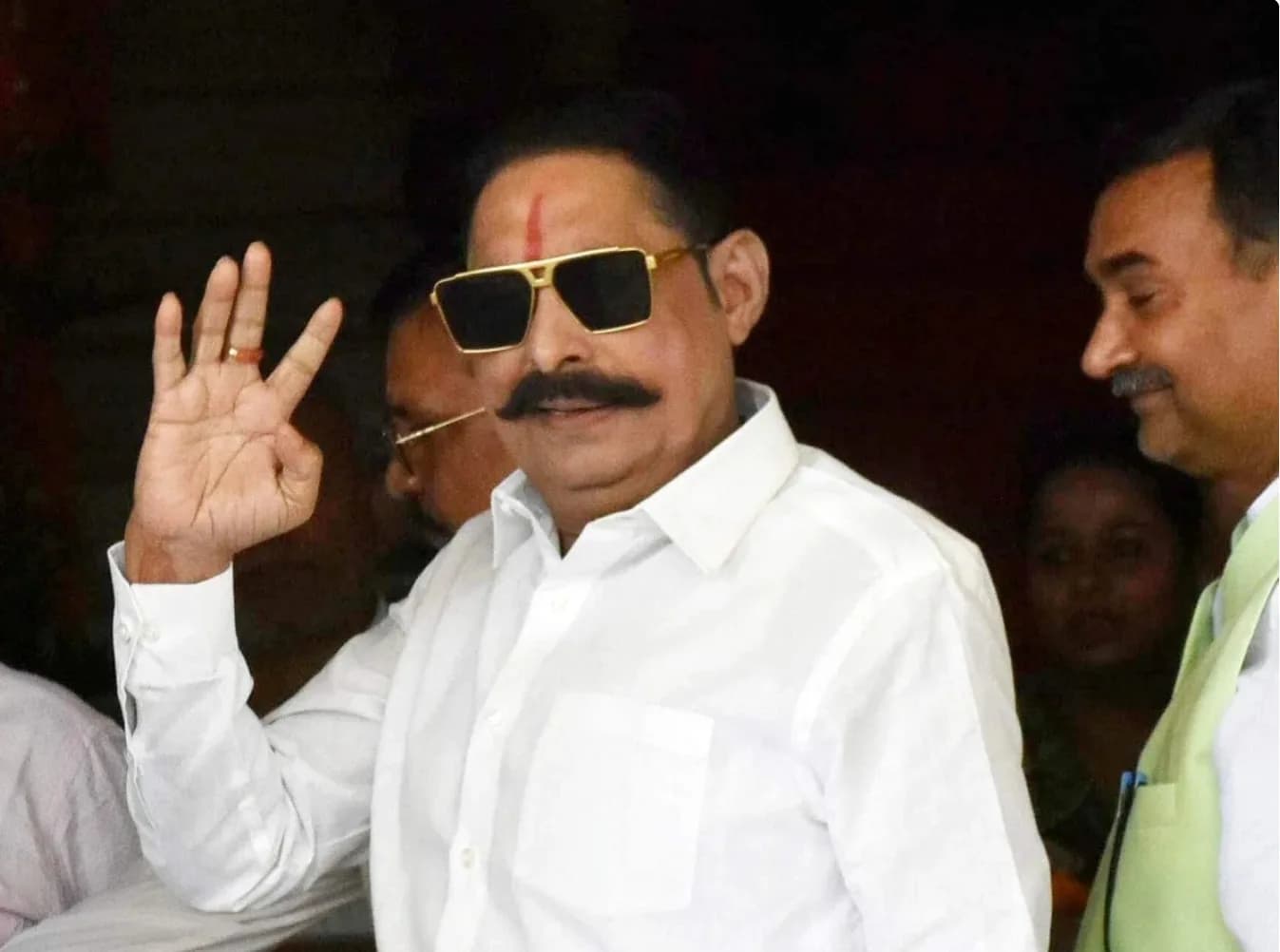 एक आदमी हाथ हिला रहा है और धूप का चश्मा पहने हुए है।